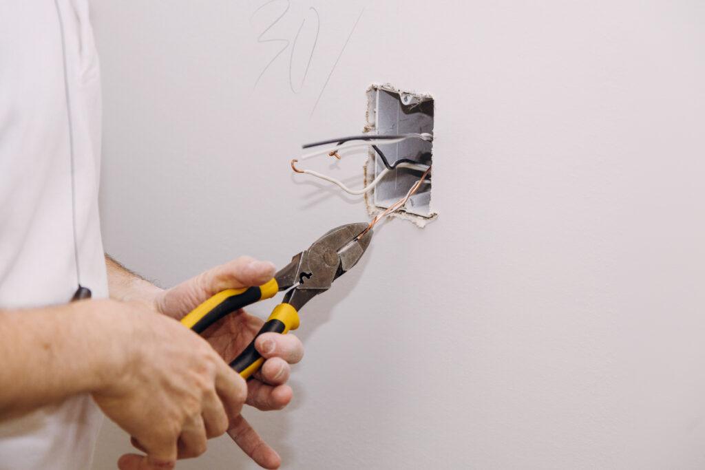 Electrician preparing wires in a wall electrical box