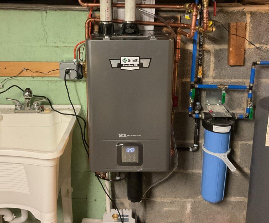 Wall-mounted tankless water heater beside a whole-home water filter